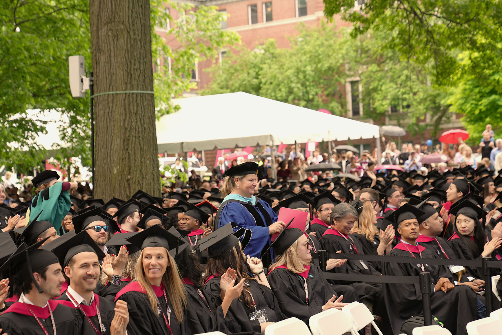 Dean Nancy Coleman walks through a crowd of seated Harvard Extension School graduates.